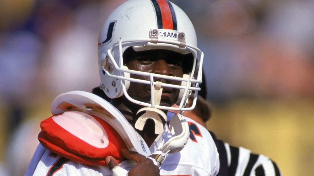 Wide receiver Michael Irving #47 of the University of Miami Hurricanes runs on the field as he tries to adjust his uniform over his shoulder pads during a 1987 NCAA game. (Source: Allen Steele/Getty Images)