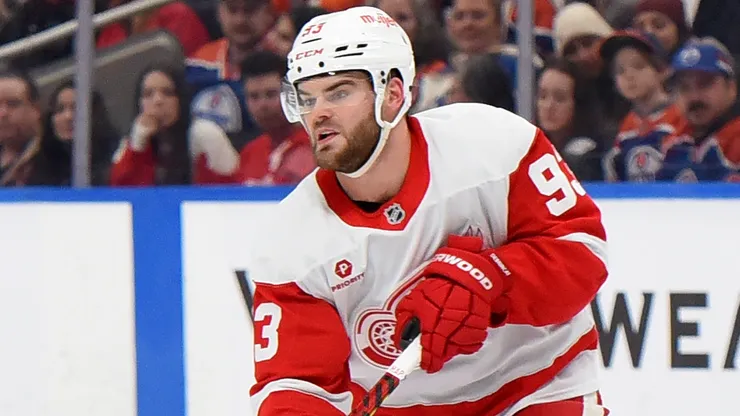 Alex DeBrincat #93 of the Detroit Red Wings makes a pass under pressure.