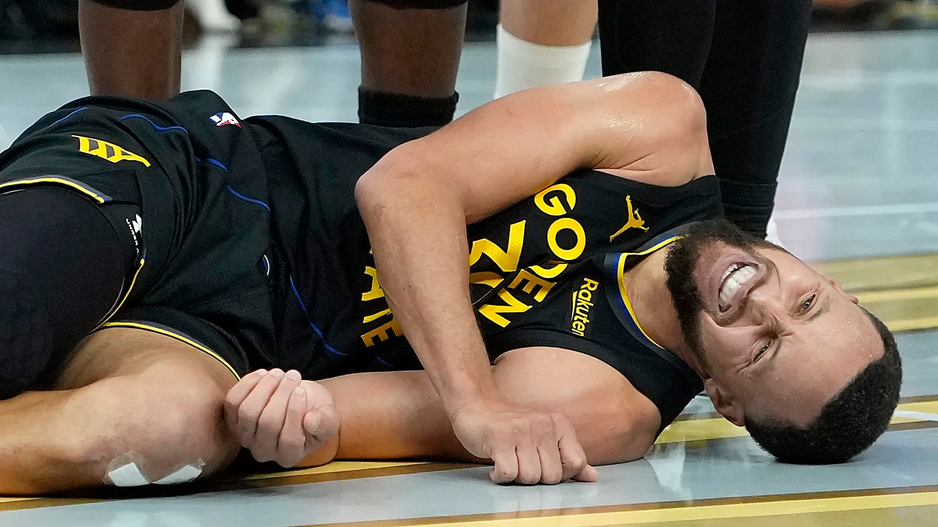 Stephen Curry of the Golden State Warriors lays on the floor in pain.