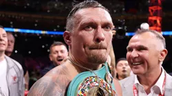 Oleksandr Usyk looks on whilst wearing the title belts.