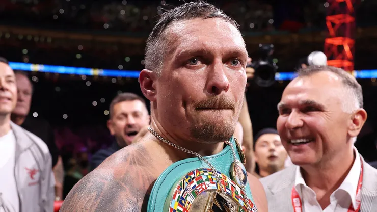 Oleksandr Usyk looks on whilst wearing the title belts.