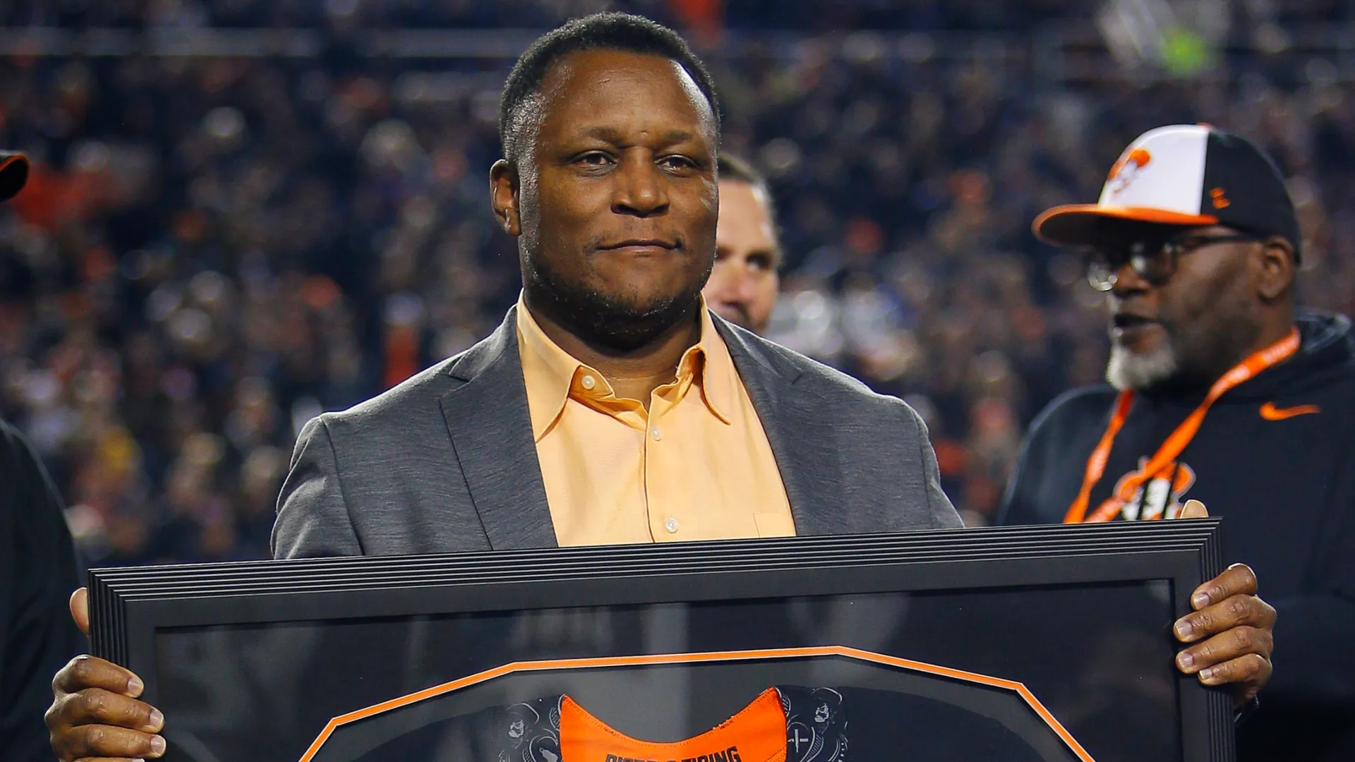 Barry Sanders of the Oklahoma State Cowboys holds up a jersey commemorating his induction into the ring of fame in 2021. (Source: Brian Bahr/Getty Images)