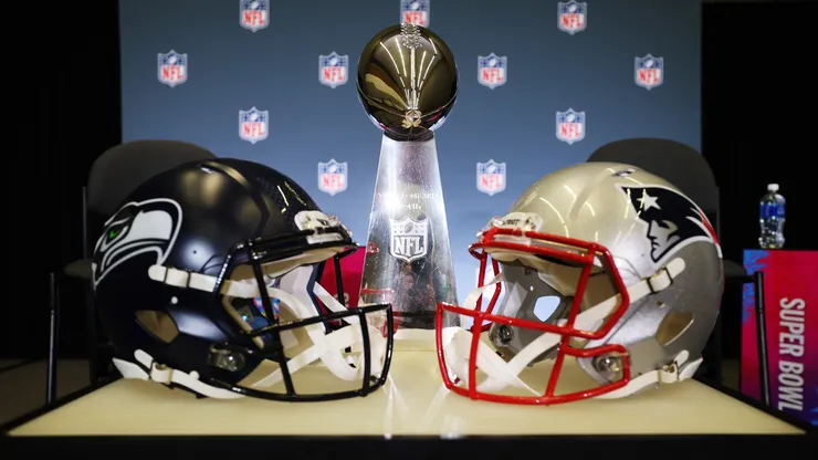 The Vince Lombardi Trophy is framed by the Seattle Seahawks and New England Patriots helmets.