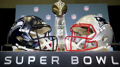 The Vince Lombardi Trophy is framed by the Seattle Seahawks and New England Patriots helmets in 2026.

