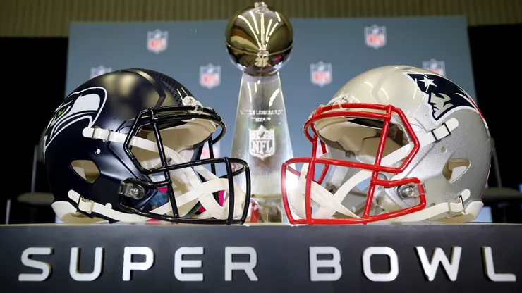 The Vince Lombardi Trophy is framed by the Seattle Seahawks and New England Patriots helmets in 2026.