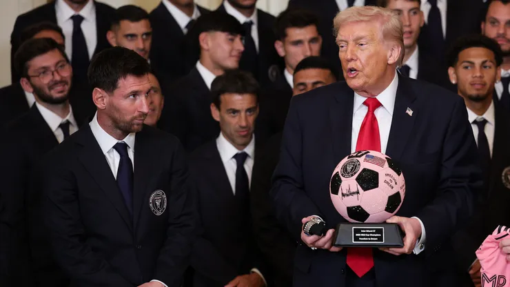 President Donald Trump receives gifts as Lionel Messi looks on.