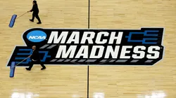 A cleaning crew mops the center court 2025 March Madness logo during practice.