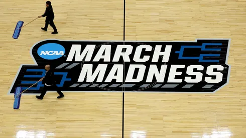 A cleaning crew mops the center court 2025 March Madness logo during practice.