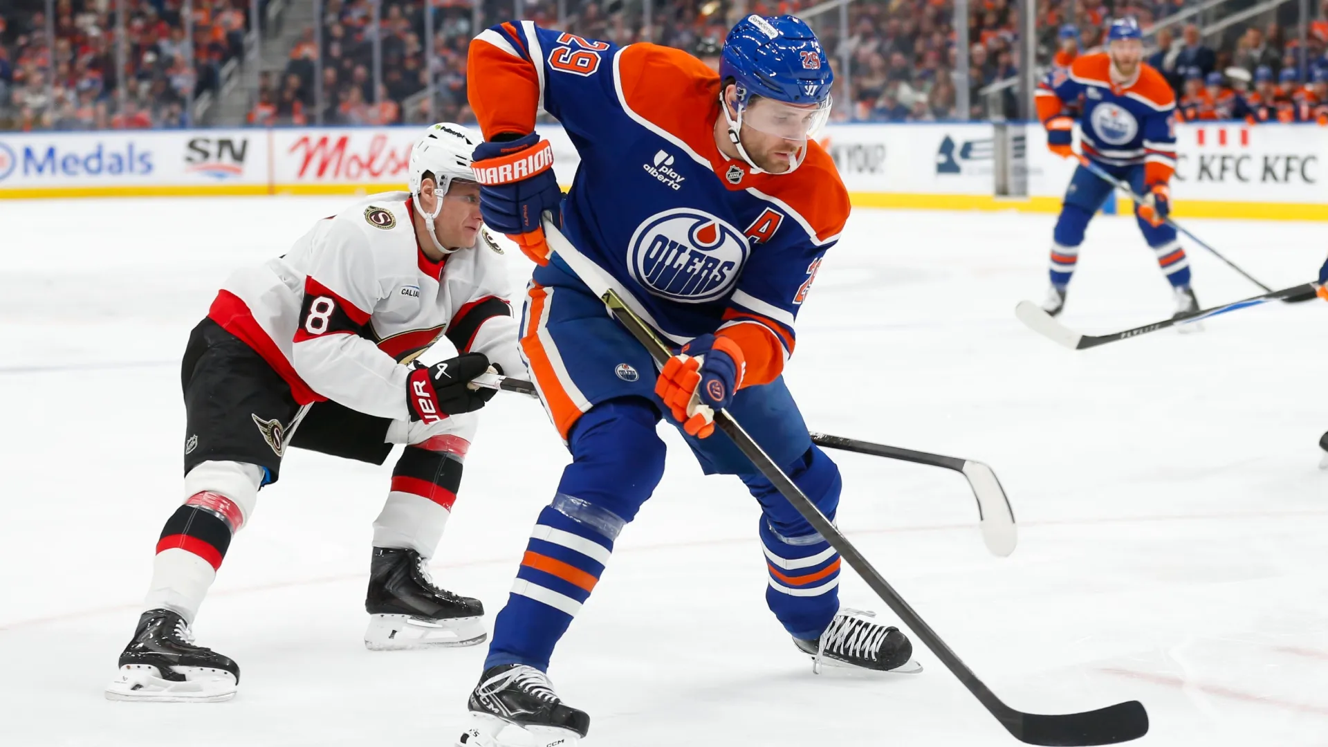 Leon Draisaitl #29 of the Oilers skates against Tim Stutzle #18 of the Senators. Codie McLachlan/Getty Images