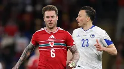 Joe Rodon of Wales runs with the ball while under pressure from Haris Tabakovic of Bosnia and Herzegovina.