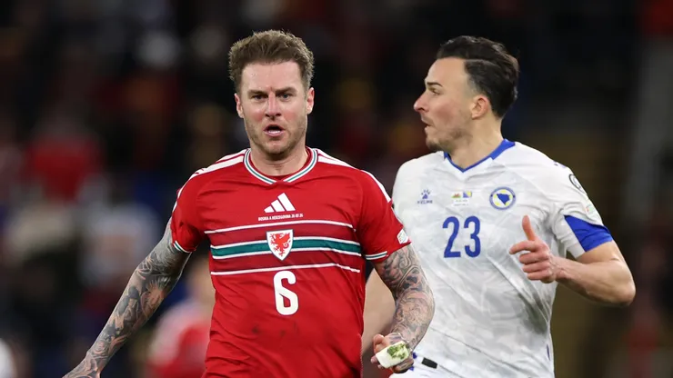 Joe Rodon of Wales runs with the ball while under pressure from Haris Tabakovic of Bosnia and Herzegovina.
