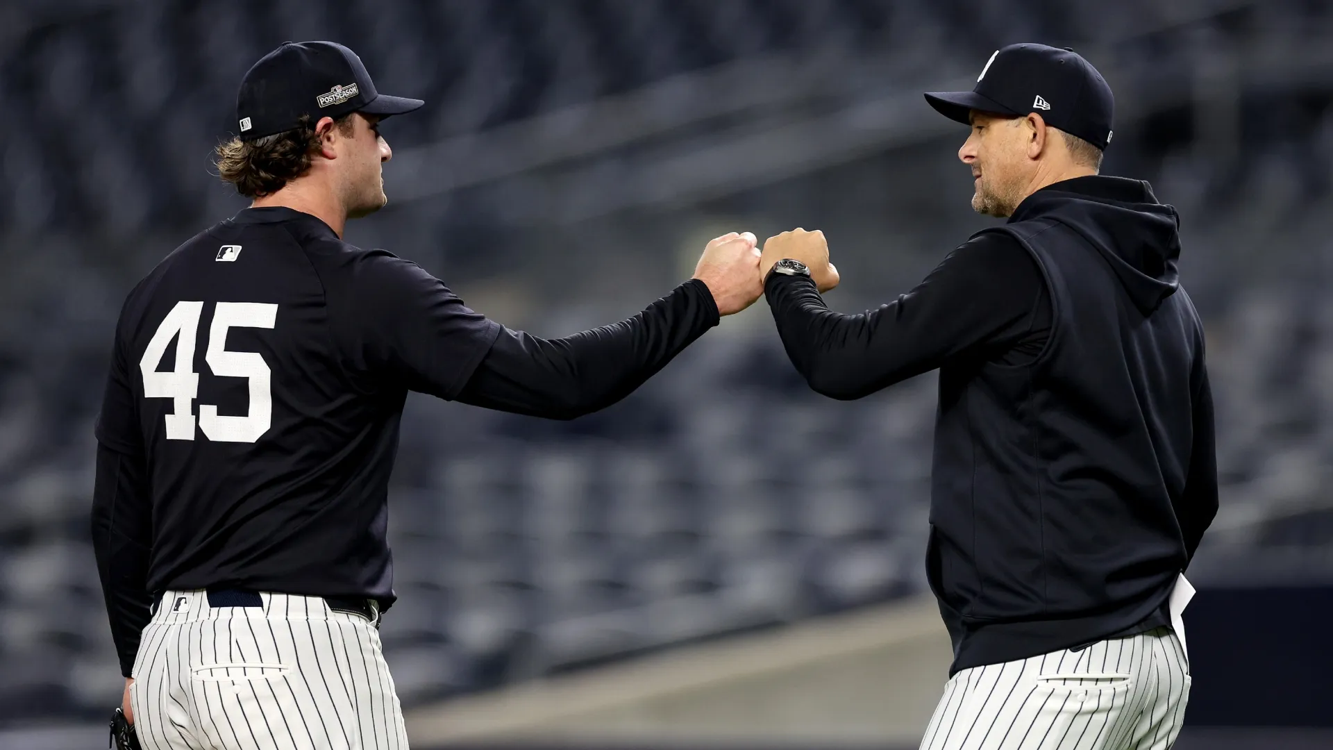 Gerrit Cole #45 and Aaron Boone #17 of the Yankees fist bump during a workout. Luke Hales/Getty Images