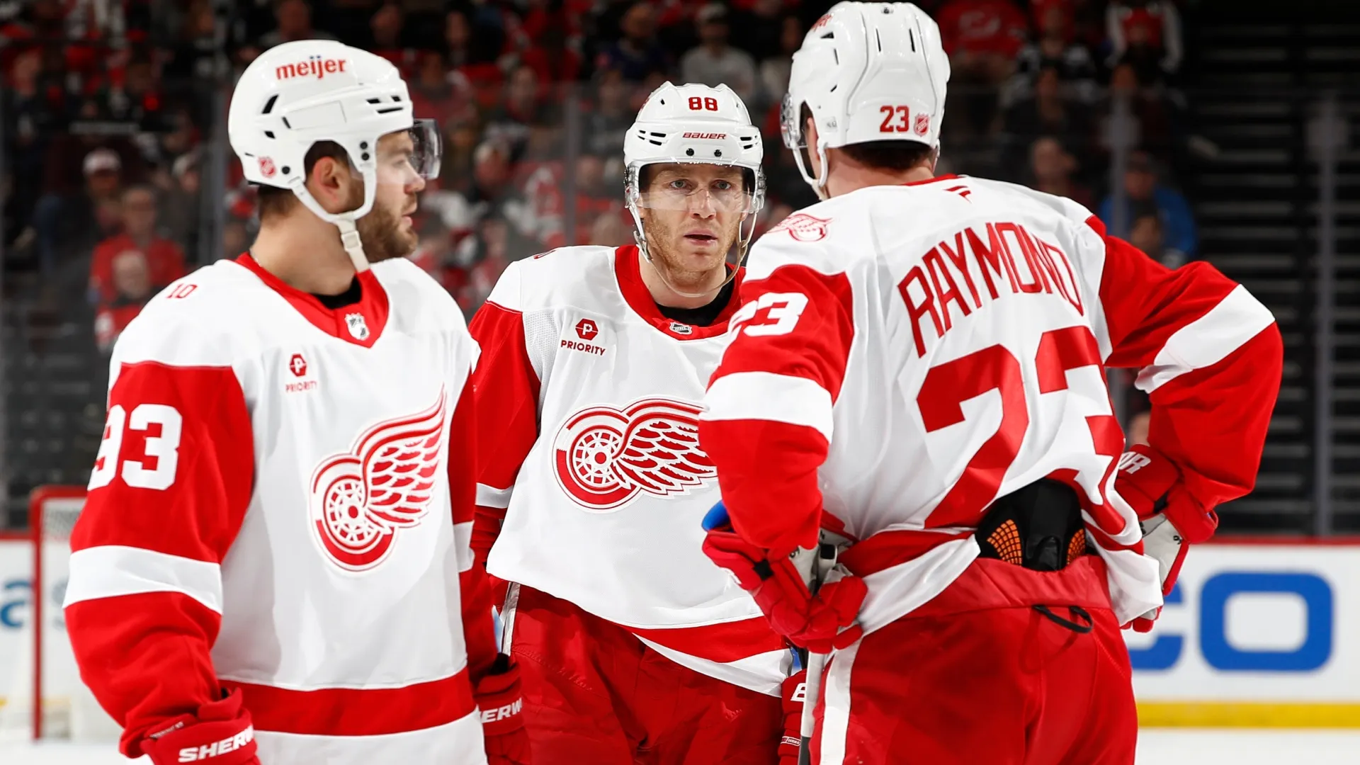 Alex DeBrincat #93 and Lucas Raymond #23 talk with Patrick Kane #88 with the Red Wings. Sarah Stier/Getty Images