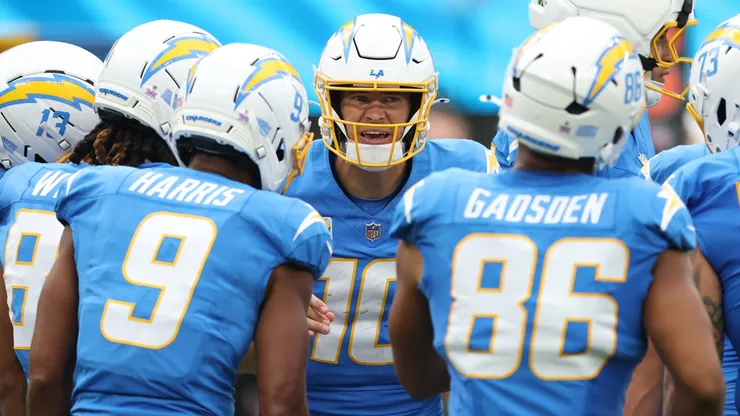 Justin Herbert #10 of the Los Angeles Chargers huddles with teammates