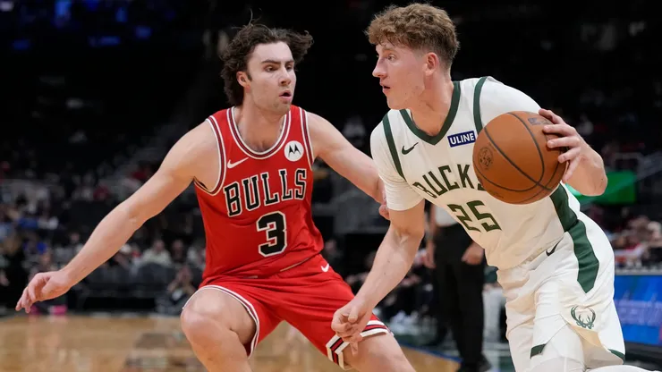 Kasparas Jakucionis #25 of the Milwaukee Bucks dribbles the ball against Josh Giddey #3 of the Chicago Bulls.