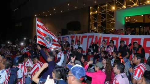 Aficionados realizando un banderazo de Chivas.