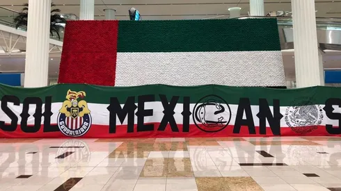 Aficionados de Chivas reciben la bienvenida a Dubái por el piloto del avión.