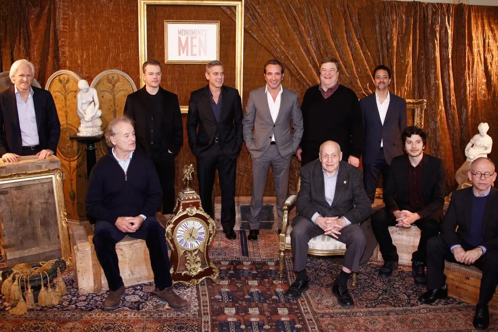 De izquierda a derecha: el guionista Robert M. Edsel, los actores Bill Murray, Matt Damon, George Clooney, Jean Dujardin, el “Hombre de los Monumentos” Harry Hettlinger, el actor John Goodman, el productor Grant Heslov, los actores Dimitri Leonidas y Bob Balaban, asisten a una sesión de fotos, en el Hotel Le Bristol el 12 de febrero de 2014 en París, Francia. Imagen: Getty Images.
