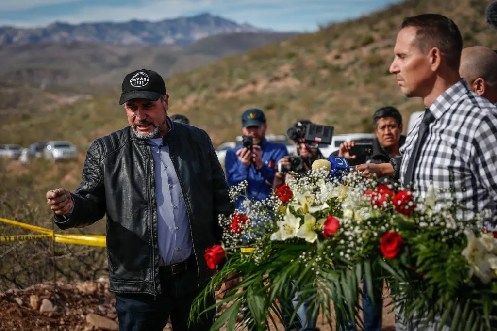 Adrián LeBaron, padre de Rhonita María Miller, quien murió junto con cuatro de sus hijos, toma en su mano un puñado de cenizas en el lugar del ataque mientras Bryan LeBaron, familiar de las víctimas, sostiene una ofrenda floral durante el día de la reunión privada con el presidente de México Andrés Manuel López Obrador en La Mora el 12 de enero de 2019 en Bavispe, Sonora. Imagen: Getty Images.