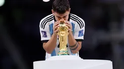 Paulo Dybala besando la Copa del Mundo en el escenario sobre el césped del Estadio de Lusail.