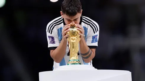 Paulo Dybala besando la Copa del Mundo en el escenario sobre el césped del Estadio de Lusail.