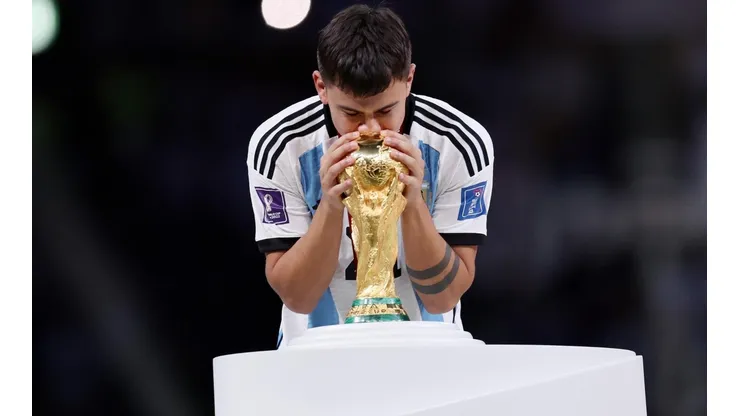 Paulo Dybala besando la Copa del Mundo en el escenario sobre el césped del Estadio de Lusail.