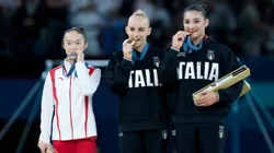 Zhou Yaqin mordiendo la medalla junto a las gimnastas italianas.