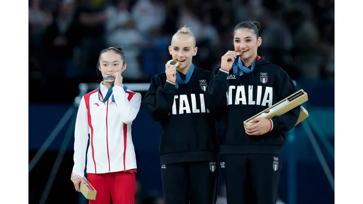 Zhou Yaqin mordiendo la medalla junto a las gimnastas italianas.