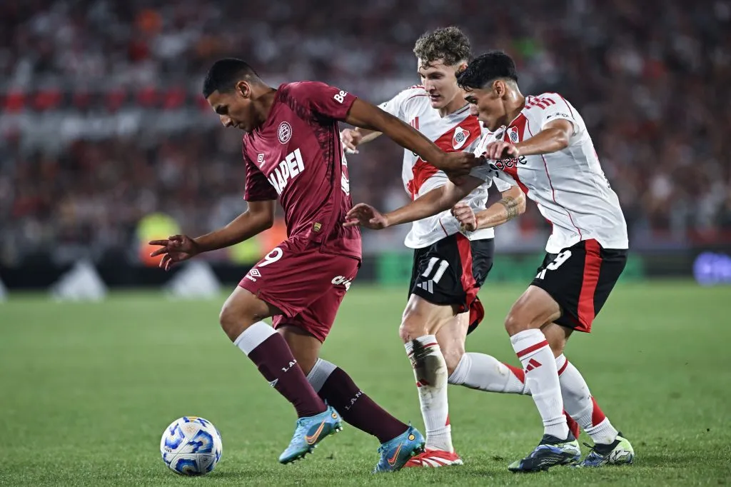Agustín Medina protege la pelota ante Facundo Colidio y Santiago Lencina en el último River vs. Lanús. (Rodrigo Valle/Getty Images)