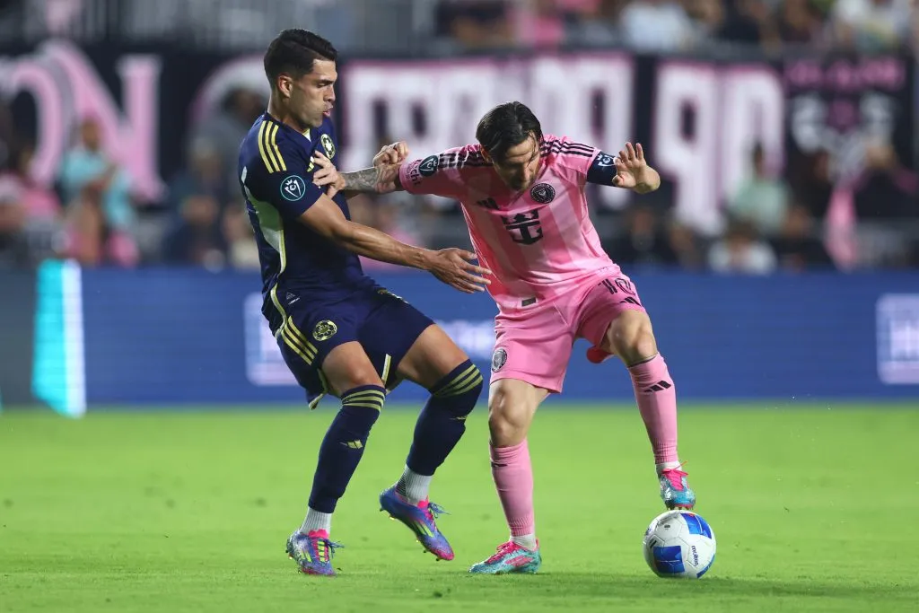 Daniel Ríos disputa una pelota con Messi.