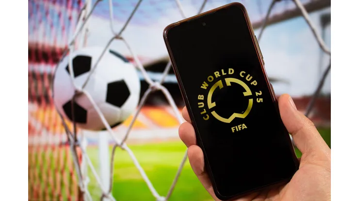 3A0YA55 BOGOTA, COLOMBIA - MARCH 05 OF 2025 A male hand holding a smartphone with fifa club world cup golden logo and blurred football ball at background