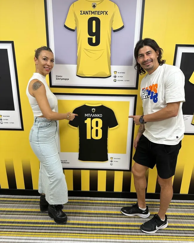 Blanco, su esposa y la camiseta histórica que está en el museo del AEK Atenas. Foto IG.