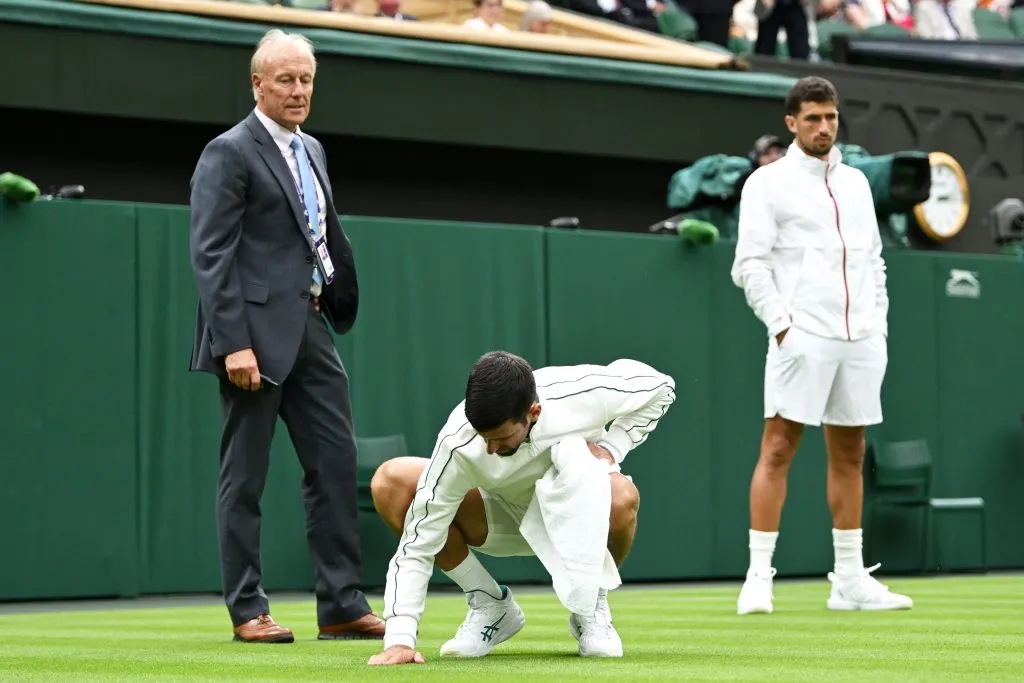 Tras la lluvia, Nole toca el césped de la central de Wimbledon ante la atenta mirada de Cachín. (Foto: Getty).