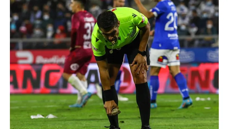 El árbitro del compromiso recogiendo una piedra que cayó a la cancha.