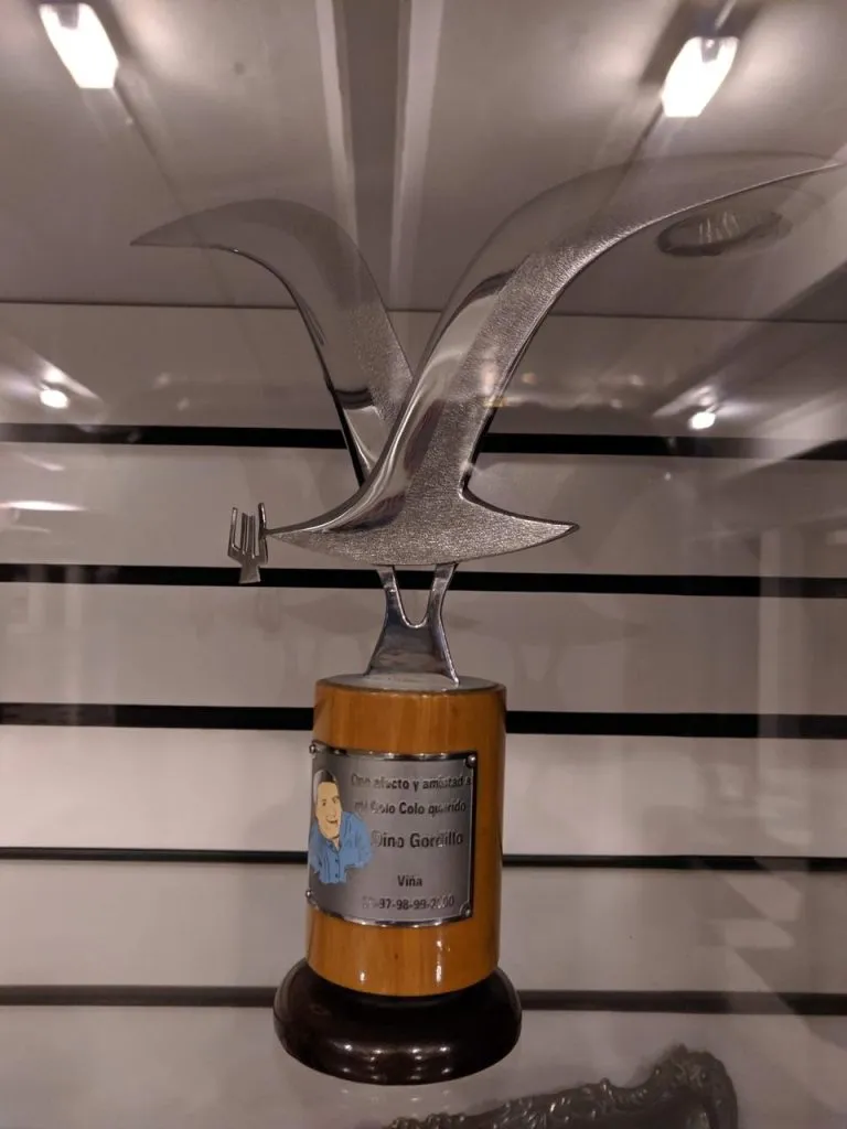 “Con afecto y amistad a mi Colo Colo querido”, Dino Gordillo, fue la placa que le agregó el artista al galardón que entregó a Colo Colo. El humorista triunfó en Viña 96, 97, 98, 99, 2000, 2011 y 2019.