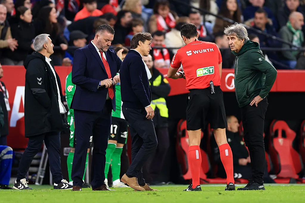SEVILLE, SPAIN – NOVEMBER 30: Referee, Jose Luis Munuera Montero talks to Matias Almeyda, Head Coach of Sevilla FC, and Manuel Pellegrini, Head Coach of Real Betis, after they throw water bottles on the floor leading to an interruption in play during the LaLiga EA Sports match between Sevilla FC and Real Betis Balompie at Estadio Ramon Sanchez Pizjuan on November 30, 2025 in Seville, Spain. (Photo by Fran Santiago/Getty Images)