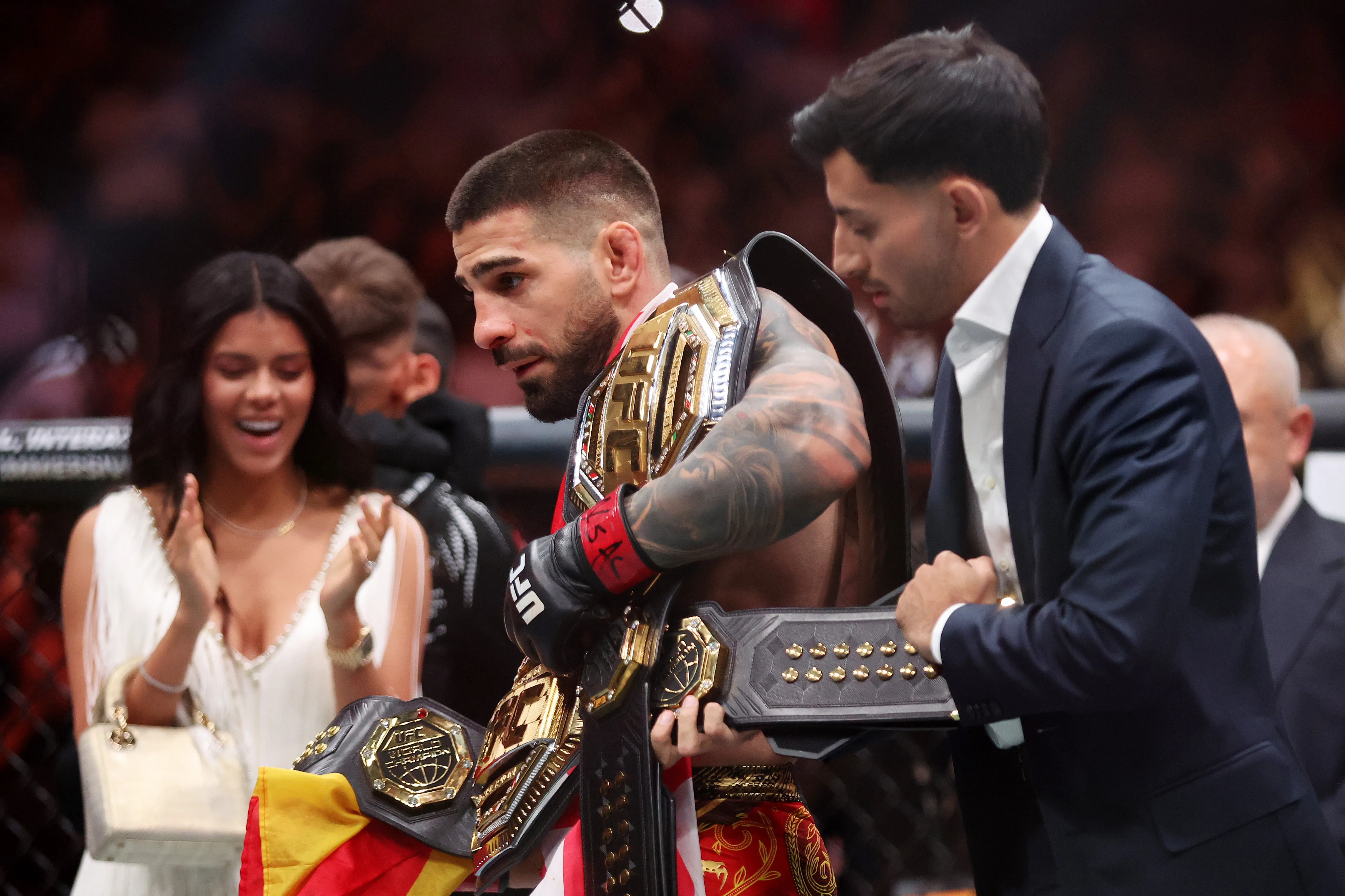 Ilia Topuria celebra con sus cinturones y Giorgina aplaude en el fondo (GETTY IMAGES)