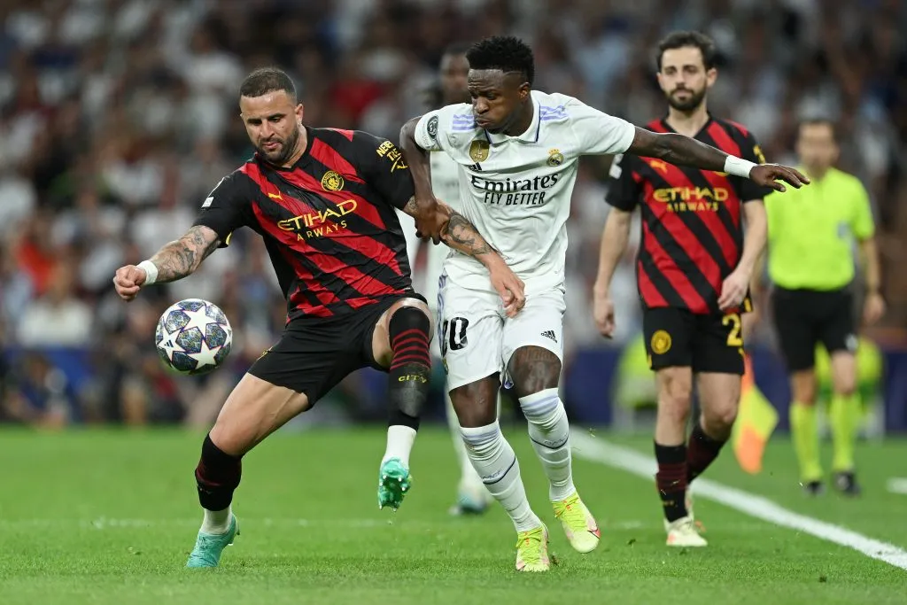 MADRID, SPAIN – MAY 09: Vinicius Junior of Real Madrid is challenged by Kyle Walker of Manchester City during the UEFA Champions League semi-final first leg match between Real Madrid and Manchester City FC at Estadio Santiago Bernabeu on May 09, 2023 in Madrid, Spain. (Photo by David Ramos/Getty Images)