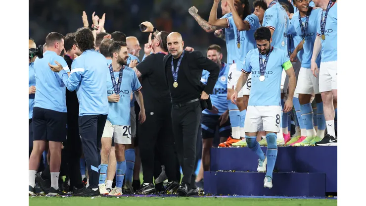 ISTANBUL, TURKEY - JUNE 10: Pep Guardiola, Manager of Manchester City, celebrates while wearing his winners medal as his players celebrates in the background after the team's victory in the UEFA Champions League 2022/23 final match between FC Internazionale and Manchester City FC at Ataturk Olympic Stadium on June 10, 2023 in Istanbul, Turkey. (Photo by Michael Steele/Getty Images)