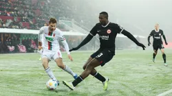AUGSBURG, GERMANY - DECEMBER 03: William Pacho of Eintracht Frankfurt shoots under pressure from Elvis Rexhbecaj of FC Augsburg during the Bundesliga match between FC Augsburg and Eintracht Frankfurt at WWK-Arena on December 03, 2023 in Augsburg, Germany. (Photo by Alexander Hassenstein/Getty Images)