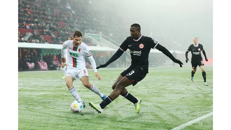 AUGSBURG, GERMANY - DECEMBER 03: William Pacho of Eintracht Frankfurt shoots under pressure from Elvis Rexhbecaj of FC Augsburg during the Bundesliga match between FC Augsburg and Eintracht Frankfurt at WWK-Arena on December 03, 2023 in Augsburg, Germany. (Photo by Alexander Hassenstein/Getty Images)