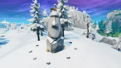 Busca entre una cámara de cine en un sótano, una cabeza de piedra nevada y un gran vehículo de oro llamativo en Fortnite