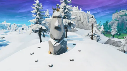 Busca entre una cámara de cine en un sótano, una cabeza de piedra nevada y un gran vehículo de oro llamativo en Fortnite