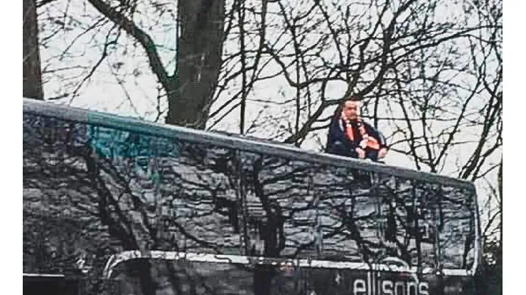 La imagen del joven sentado en el techo del autobús.