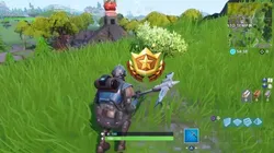 Busca entre un hombre de roca gigante, un Tomate coronado y un árbol cercado en Fortnite