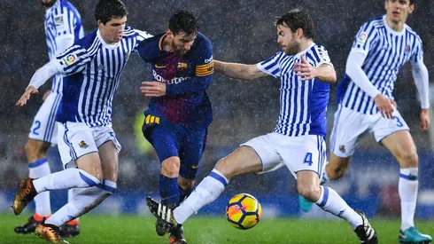 NO LO PUEDEN PARAR. Lionel Messi bajo la lluvia y ante dos jugadores de la Real Sociedad (Foto: Getty).
