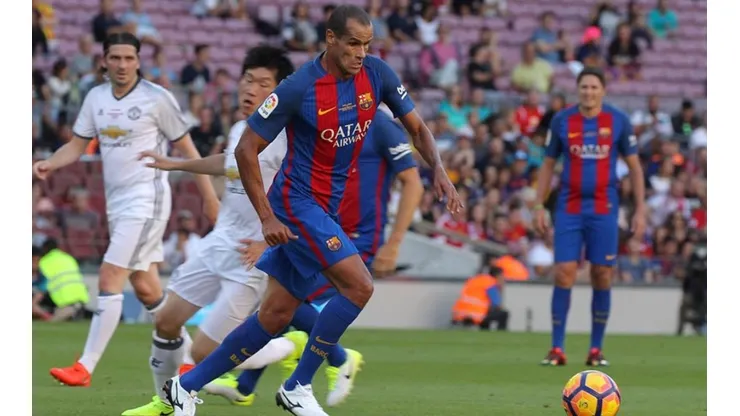 PARTIDO DE LEYENDAS. Rivaldo pasa en velocidad en un encuentro en el Camp Nou con ídolos del Manchester United.