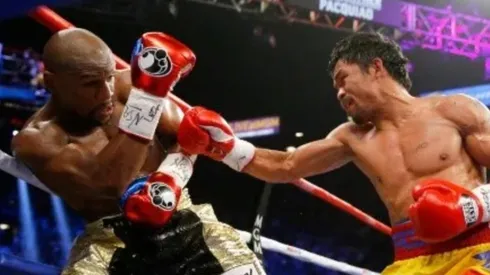 Manny Pacquiao lanza un derechazo a Floyd Mayweather Jr. durante su combate por la unificación del peso welter.
