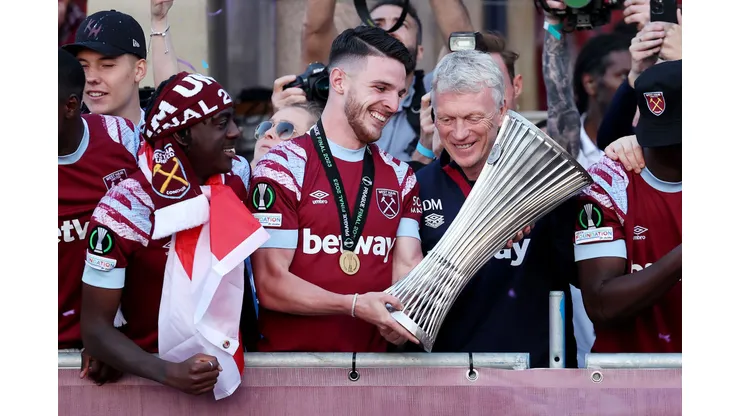LONDON, ENGLAND - JUNE 08: Declan Rice of West Ham United admires the Europa Conference League trophy with David Moyes, Manager of West Ham United, as players of West Ham United celebrate on a balcony whilst looking out over a crowd of fans during the West Ham United trophy parade on June 08, 2023 in London, England. West Ham defeated ACF Fiorentina in the Europa Conference League Final on June 7th. (Photo by Eddie Keogh/Getty Images)