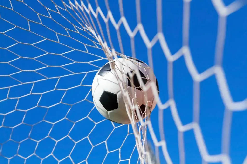 Imagem de bola de futebol contra rede de uma baliza